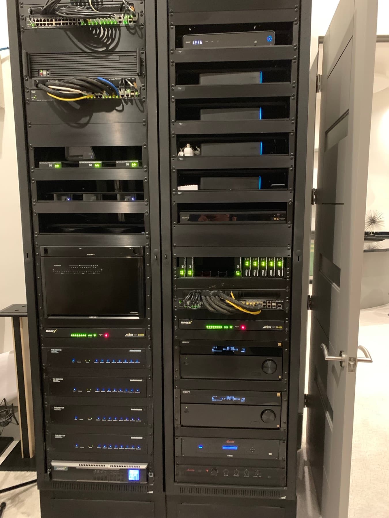 Finished two-bay home AV rack, powered on, with Savant control, video-over-IP distribution, network switches, amplifiers and surge protection